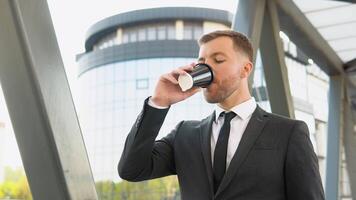 giovane fiducioso uomo d'affari potabile caffè vicino il attività commerciale centro video