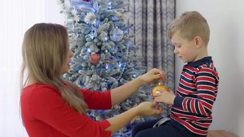 Little boy helping his mom to decorate christmas tree video