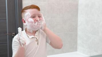 Funny boy in the bath smears his face with shaving cream, the child imitates an adult dad shaves video