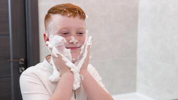 Funny boy in the bath smears his face with shaving cream, the child imitates an adult dad shaves video