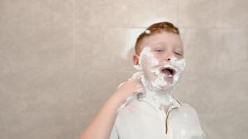 Funny boy in the bath smears his face with shaving cream shows a sign of consent with his thumb up video