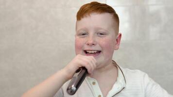 Little boy is shaving his face with electric razor in the bathroom. Funny boy having fun while shaving in bathroom video