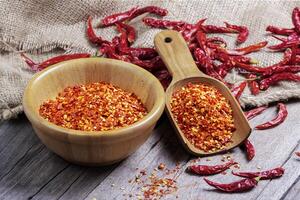 Dried chilies with chili powder, pepper, and red paprika in a wooden bowl Spicy seasoning Healthy food, top view photo