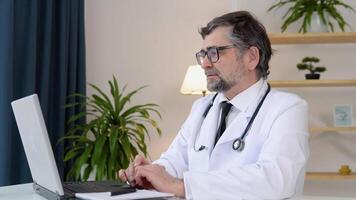 Senior doctor talking during chat on laptop video