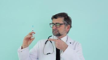 Doctor holds a syringe and vaccine bottle at the hospital on blue background. Health and medical concepts video