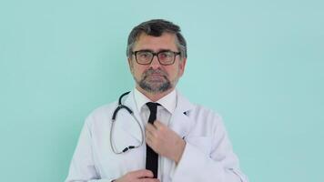 portrait de une Sénior médecin dans blanc costume avec stéthoscope correction attacher sur bleu Contexte video