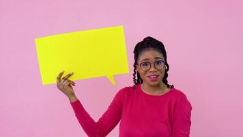 Cute young african american girl stands with posters for expression on a solid pink background. A place for advertising slogans video