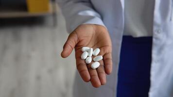 Young indian woman doctor holds pills in hand. Close up view of hands video