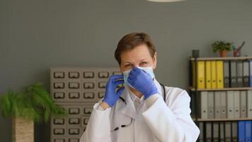 Positive senior female doctor puts on a protective blue mask. Virus Protection video