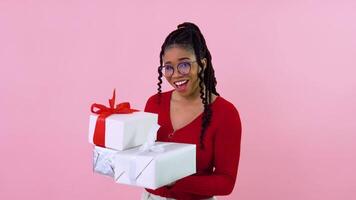 Cute young african american girl holding three gift boxes. Teen girl in red clothes holds white boxes with red and white ribbons. Birthday gift video