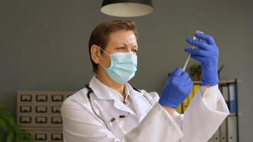 Senior female doctor in a protective mask with a vaccine syringe in his hands video