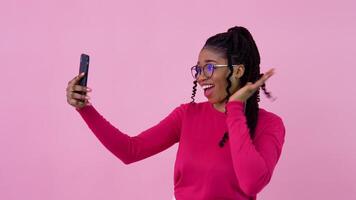 Cute young african american girl in pink clothes communicates by link. Teen girl standing on a solid pink background video