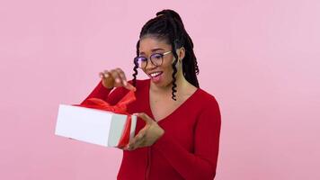 Young african american girl in red clothes holding a white box with red ribbon. Birthday gift video