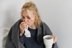 retrato de mujer atrapando un frío, quedarse hogar enfermo, Bebiendo té, estornudos en servilleta, soplo nariz, tiene codicioso síntomas foto