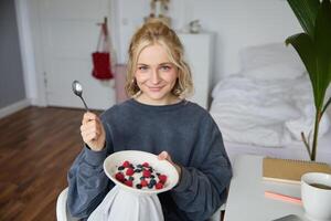 Portrait of young vlogger, content creator, showing her homemade breakfast on camera, eating dessert, smiling and looking happy photo