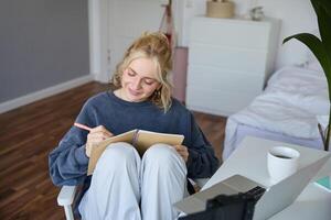 Portrait of cute, smiling young social media content creator, girl records on digital camera and stabiliser, holds notebook, talks to audience, vlogging in her room photo