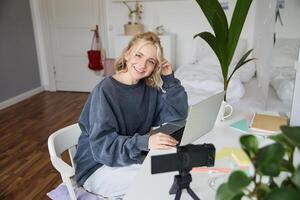 Portrait of young beautiful woman, social media influencer, recording tutorial, lifestyle vlog, creating content in her room using digital camera photo