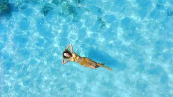 Woman swims and relaxing in tropical blue sea. Aerial top down view, vacations in tropics video