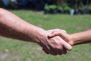 Close-up shot of man shaking hands with woman in the garden. Concept of teamwork. photo