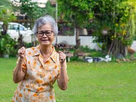 Portrait of happy senior woman clenching fists. Excited for success with arms raised celebrating victory smiling. photo