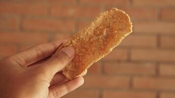 photo of hand holding a typical Indonesian food, namely rambak crackers