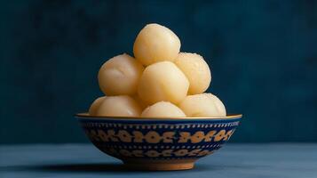 AI generated The rasgullas kept in a shallow bowl, dipped in sugar syrup.  Luxuious indian background. Plain deep navy blue background. Generated by artificial intelligence. photo