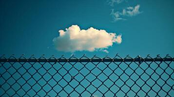 Clouds in the blue sky behind an open chain link fence. photo