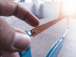 Checking sharpness and showing the correct direction of the hacksaw teeth. photo