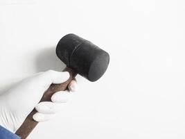 Man's hand with gloves holds a rubber hammer isolated on white background.Carpenter tools concept. photo