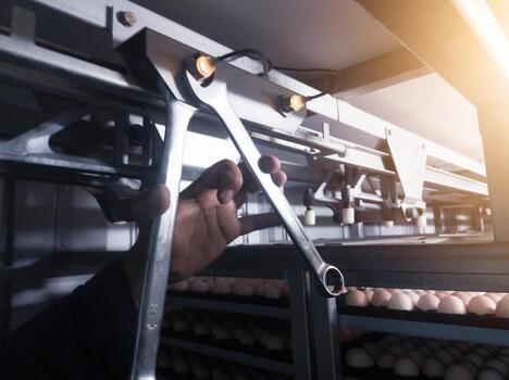 Check and adjusting the turning sensor on the incubation hatchering machine. Twchnician adjusting turning sensor with tools wrench. photo