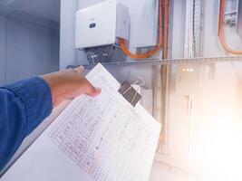 An inspector is pointing to the solar panel inverter module, having the concept of checking and monitoring the solar panel inverter. comissioning concept. photo
