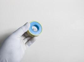 Man's hand with gloves holds a seal tape isolated on white background. Plumbing equipment concept. photo