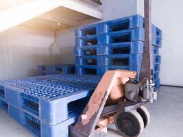 Hand pallet jack and some blue pallet on the distribution warehouse area. photo