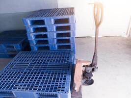 Hand pallet jack and some blue pallet on the distribution warehouse area. photo