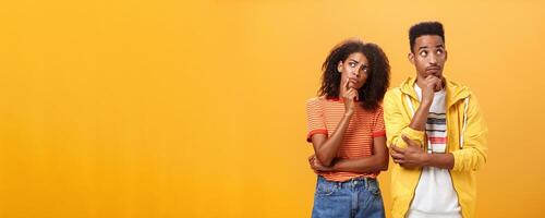 Two brains better than one. Thoughtful couple of african american friends in stylish urban outfit standing in thinker pose looking up determined and focused making up plan how spend evening photo