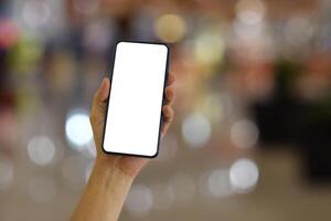 Hand holding smartphone with blank screen on bokeh light background photo