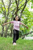 Portrait of child girl running and smiling in green park. photo
