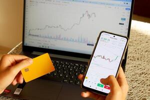 An investor who buys coins with a credit card. bitcoin chart on computer in background photo