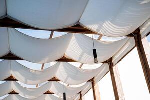 A hinged fabric roof, a summer patio, protection from the sun and heat, the interior of an outdoor cafe, white fabric on the ceiling, a restaurant in the desert. photo