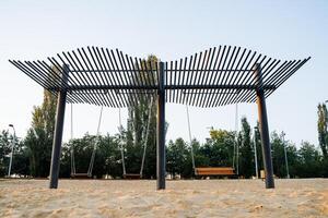 Modern swings on chains, wooden seats hang on a chain, a large swing for relaxing by the sea, a beach area of fine sand, an attraction for children. photo