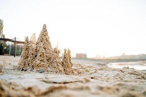 Sand castle in the rays of sunlight, the sea coast within the city, the dawn on the beach, the castle of sand. photo