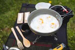 Delicious delicious scrambled eggs cooked in camping conditions on a tourist burner, hiking cuisine, breakfast in the mountains, cutlery, climber's equipment. photo