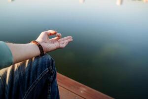 Chinmudra hand rests on the knee, fingers gathered in a yoga symbol, meditation practice, elements of a practicing person, Zen on the sea in silence photo