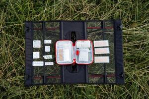 First aid kit view from above, the layout of medicines on the table against the background of nature, a travel bag with medicines, a camping set of tablets. photo