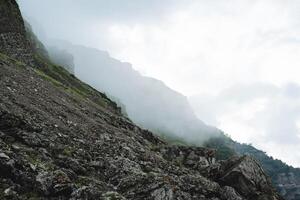 el rocoso montañas de daguestán niebla llena el Valle de el garganta, el paisaje melancólico mañana, Roca piedra desde el montaña, nublado clima. foto