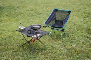 Camping furniture, compact equipment, camping equipment, camping utensils are on the table, a folding chair, a gas burner, a kettle. photo