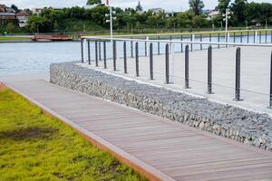 A wooden road descends to the pond, an observation deck in the city park by the lake, landscape design construction of a park for walking and recreation. photo