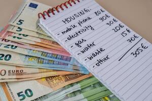 Euro cash money with notebook handwritten housing expenses. Counting bills for electricity, gas, water. Concept of Efficient Consumption and Economy. Spending habits photo