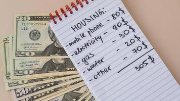 Dollar cash money with notebook handwritten housing expenses. Counting bills for electricity, gas, water. Concept of Efficient Consumption and Economy. Spending habits photo