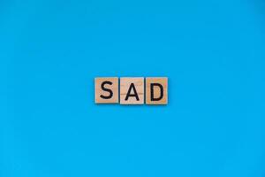 Seasonal affective disorder - text of wooden blocks on blue bright background. Concept of depression mood stress and anxiety. SAD wellbeing photo